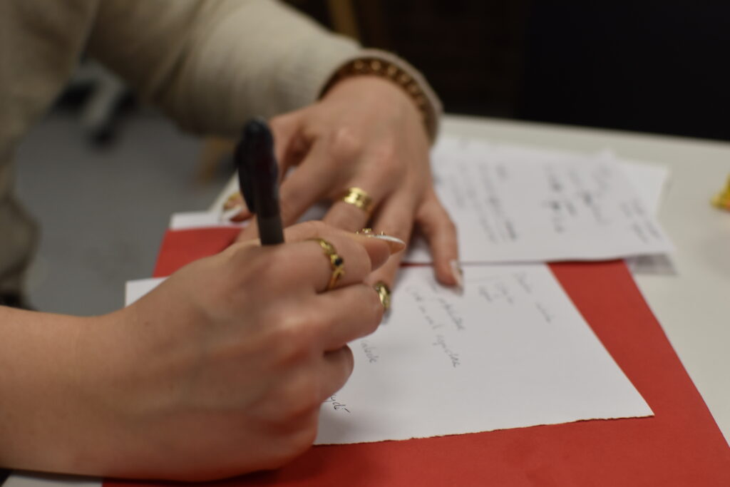 Photo des mains de l'intervenante des ateliers d'écriture en train de rédiger.