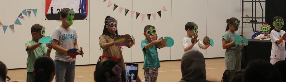 Sur scène, les enfants portent des masques qu'ils ont fabriqué spécifiquement pour le spectacle