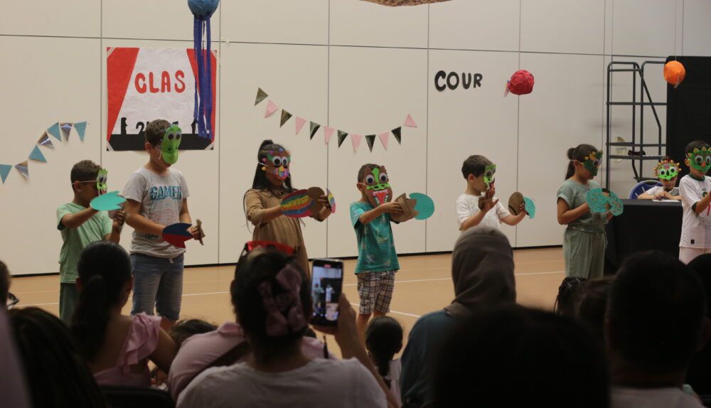 Sur scène, les enfants portent des masques qu'ils ont fabriqué spécifiquement pour le spectacle