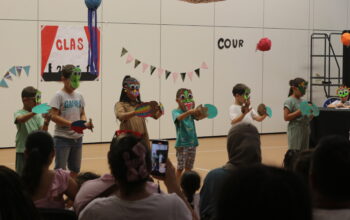Sur scène, les enfants portent des masques qu'ils ont fabriqué spécifiquement pour le spectacle