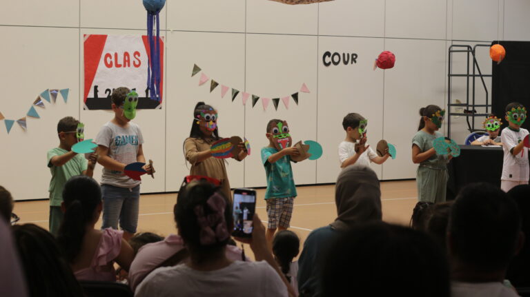 Sur scène, les enfants portent des masques qu'ils ont fabriqué spécifiquement pour le spectacle