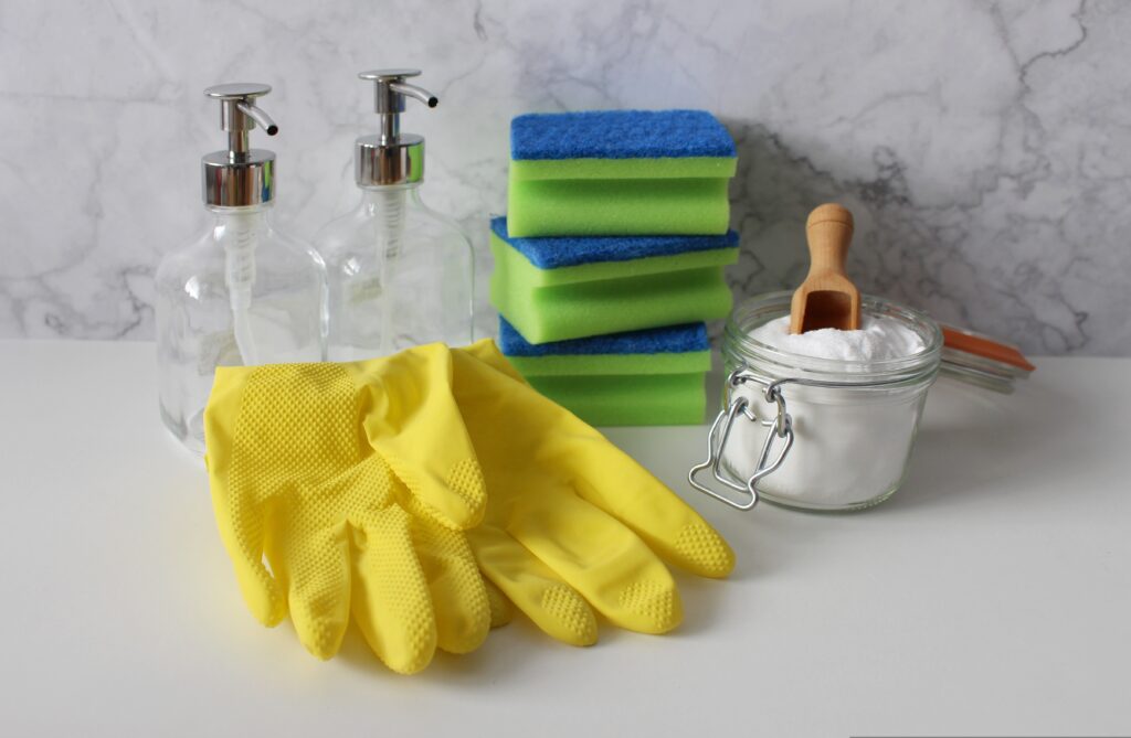 Une surface avec des gants, des épondes et un bocal avec du bicarbonate de soude